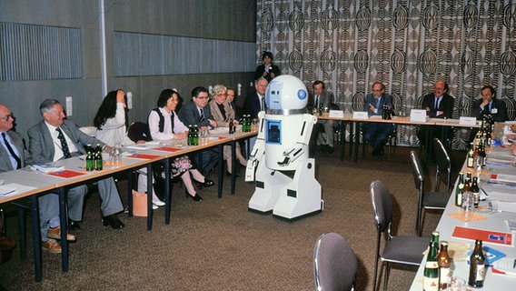 Ein Roboter steht in einem mit Menschen besetzten Konferenzraum im CCH. © Hamburg Messe und Congress 
