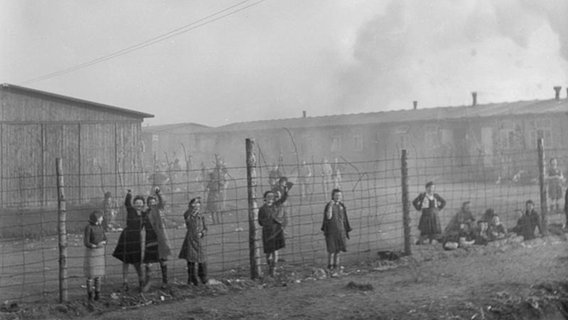 Menschen stehen an einem Zaun im Konzentrationslager Bergen-Belsen. © Imperial War Museum 