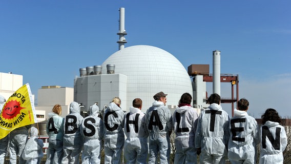Atomkraftgegner fordern am 27. Jahrestag der Tschernobyl-Katastrophe am 21.04.2013 vor dem AKW Brokdorf mit Schriftzügen auf der Kleidung die Abschaltung des Kernkraftwerks. © picture alliance / dpa Foto: Carsten Rehder