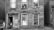 Eine Gruppe von Menschen schaut in Chicago aus den Fenstern eine Hauses (April 1941) © picture alliance / Glasshouse Images | Circa Images 