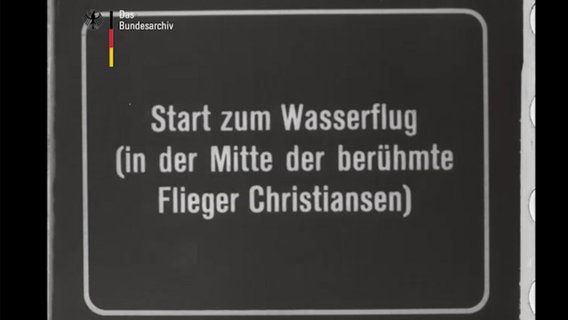 Auf einer Stummfilm-Tafel steht "Start zum Wasserflug (in der Mitte der berühmte Flieger Christiansen) © Bundesarchiv Foto: Screenshot