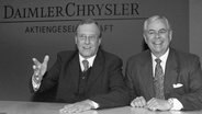 Daimler-Benz-Chef Jürgen Schrempp (l) und Chrysler-Chef Robert Eaton (Archivbild vom 07.05.1998) scherzen mit Journalisten bei der Ankündigung der Fusion beider Unternehmen auf einer Pressekonferenz in London. © dpa Foto: Bernd Weißbrod