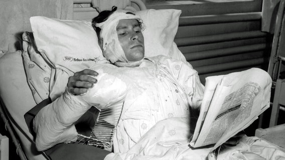 Ein während des DDR-Volksaufstandes am 17. Juni 1953 verletzter Berliner liegt mit Verbänden und Gips in einem Bett im Krankenhaus und liest Zeitung. © picture-alliance / dpa Foto: Günter Bratke