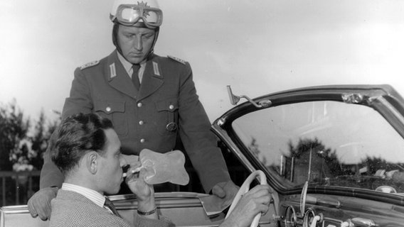 Das Foto aus dem Jahr 1953, dem Jahr der Markteinführung der berühmten Pusteröhrchen, zeigt einen Polizeibeamten der einen Alkoholtest durchführen lässt. © picture-alliance / dpa / dpaweb / Dräger 