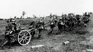 Deutsche Soldaten ziehen im Ersten Weltkrieg ein Geschütz über eine Wiese. © imago/United Archives 