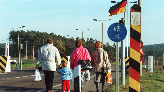 Eine Familie überquert im November 1989 mit Einkaufstüten einen geöffneten Grenzübergang zwischen DDR und BRD. © picture-alliance / dpa Foto: Wolfgang Weihs