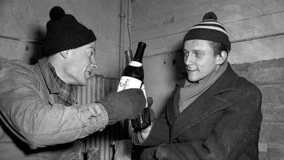 René Leudesdorff (l.) und sein Kommilitone Georg Hatzfeld stoßen am 22. Dezember 1950 im Flakbunker auf Helogland mit jewils einer Flasche Wein an im Flakkbunker © dpa Picture Alliance Foto: Jochen Blume