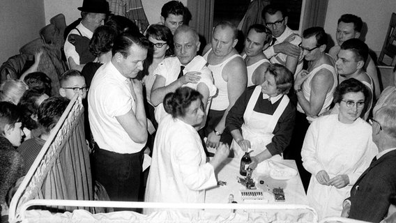 Menschen drängen sich Ende Oktober 1965 in einem der notdürftig eingerichteten Impflokale in Kulmbach in Oberfranken, um sich gegen Pocken impfen zu lassen. © picture-alliance / dpa | DB 