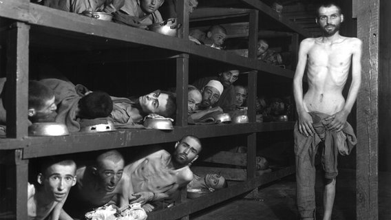 Befreite Häftlinge des Konzentrationslagers Buchenwald 1945 in den Schlafboxen des Blocks 56 im Kleinen Lager, unter ihnen der spätere Journalist und Schriftsteller Elie Wiesel (2. Reihe, 7. v. l.) © National Archives, Washington / Public Domain 