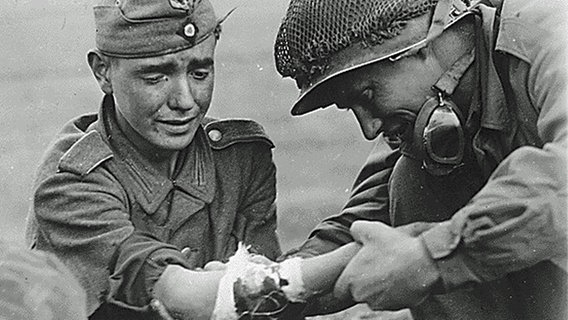 Ein amerikanischer Soldat kümmert sich um einen verletzten jugendlichen NS-Soldaten. © National Archives and Records Administration, College Park 