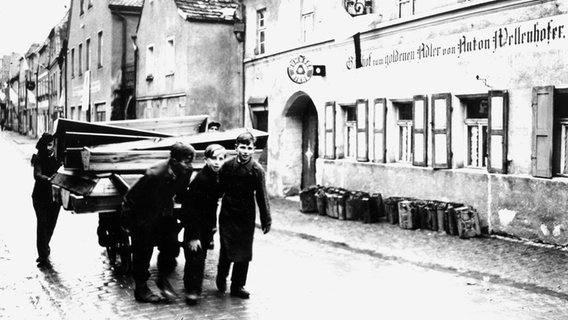 Deutsche Jungen ziehen nach Ende des Zweiten Weltkriegs eine Wagenladung Sargdeckel zu einem Stadtfriedhof,
wo die Leichen polnischer, ungarischer und russischer Juden begraben werden sollen. © National Archives and Records Administration, College Park 