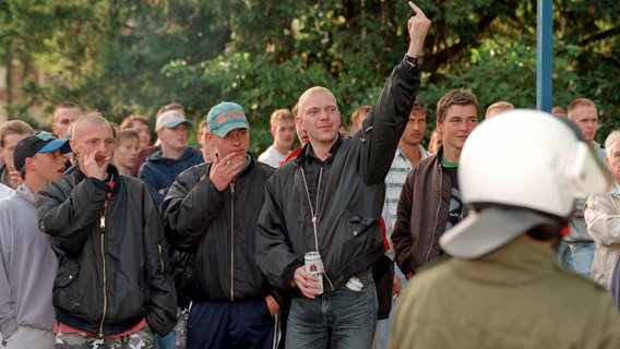 Offenbar rechts eingestellte junge Leute stehen 1996 am Rande einer Demo gegen Neonazis in Grevesmühlen - einer reckt den Mittelfinger. © picture-alliance Foto: Bernd Wüstneck