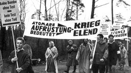 Aus Hamburg kommende Demonstranten auf ihrem Marsch am 18. April 1960: Demonstranten in Regenkleidung halten Plakate wie 'Atomare Aufrüstung bedeutet Krieg und Elend'. © picture-alliance / dpa Foto: Marek