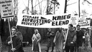 Aus Hamburg kommende Demonstranten auf ihrem Marsch am 18. April 1960: Demonstratanten in Regenkleidung halten Plakate wie 'Atomare Aufrüstung bedeutet Krieg und Elend'. © picture-alliance / dpa Foto: Marek