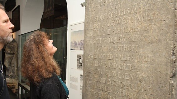 Besucher schauen sich im Museum für Hamburgische Geschichte eine Grabplatte an, die an einen Pestarzt aus dem 18. Jahrhundert erinnert. © NDR Foto: Oliver Diedrich