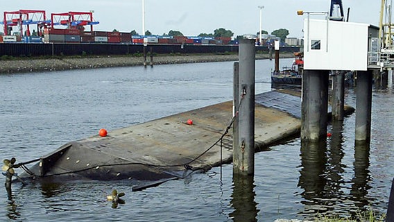 Ein Schiff liegt kieloben in einem Hafenbecken © picture alliance / AP Photo 