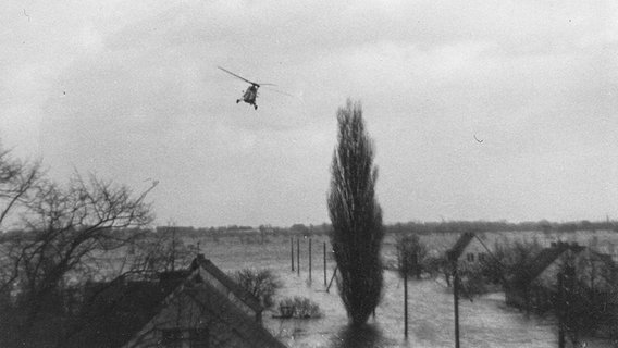 Ein Hubschrauber fliegt während der Sturmflut 1962 über Häuser am Siedenfelder Weg in Hamburg-Kirchdorf. © NDR Foto: Karl-Heinz Leptien