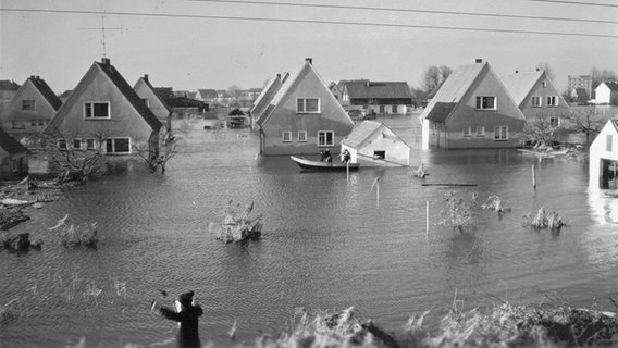 Ein Boot fährt nach der Sturmflut 1962 an Siedlungshäusern am Sandwisch in Moorfleet vorbei. © NDR Foto: Kurt Jenke