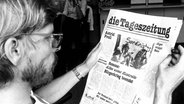 Helmut Heuse hält die Null-Nummer der "Tageszeitung" in Händen, die im September 1978 mit einer Auflage von 55.000 erschienen ist. © picture-alliance/ dpa Foto: Roland Witschel