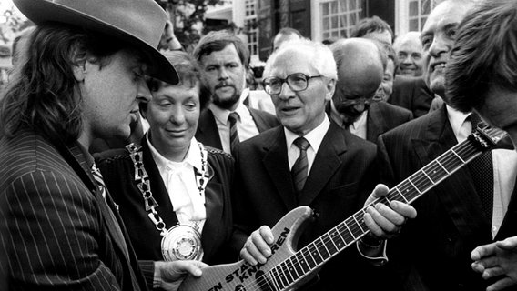 SED-Generalsekretär Erich Honecker erhält 1987 in Wuppertal von Udo Lindenberg eine Gitarre mit der Aufschrift: "Gitarren statt Knarren". © picture-alliance / dpa Foto: Franz-Peter Tschauner