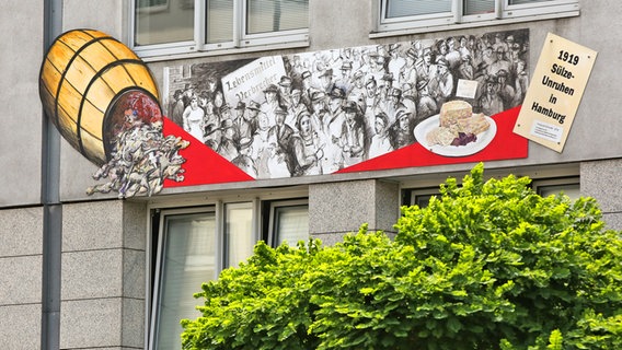 Ein Wandbild mit Szenen der Sülze-Unruhen von 1991 an der Hauswand der Hamburger Verbraucherzentrale. Ein Wandbild mit Szenen der Sülze-Unruhen von 1991 an der Hauswand der Hamburger Verbraucherzentrale. © picture alliance Foto: Bodo Marks