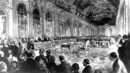 Der französische Ministerpräsident Clemenceau eröffnet im Juni 1919 in Schloss Versailles die Sitzung zur Unterzeichnung des Friedensvertrages (Zeichnung von George Scott). © picture-alliance / dpa 