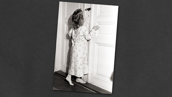 Ein kleines Mädchen im Nachthemd kann es kaum erwarten und wagt einen Blick durch das Schlüsselloch. © dpa - Report 