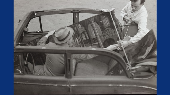 Zwei Männer transportieren ein Gemälde in einem Pkw. © Stadtarchiv Braunschweig 