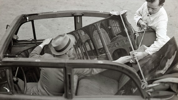 Zwei Männer transportieren ein Gemälde in einem Pkw. © Stadtarchiv Braunschweig 