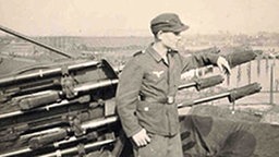 Zeitzeuge Ralph Brauer als Flakhelfer neben einem Geschütz. © NDR 