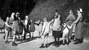 Geistig behinderte Kinder spielen mit zwei Diakonieschwestern um 1930 Ringelreihen. © dpa - Report 