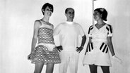 Der französische Modedesigner André Courrèges steht 1968 zwischen zwei Models, die seine Miniröcke tragen. © picture alliance/United Archives | 91050/United_Archives/TopFoto 