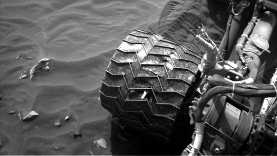 Eine Kamera fotografiert am 14. April 2022 eines der löchrigen Aluminiumräder des Marsrovers Curiosity. ©  NASA/JPL-Caltech 