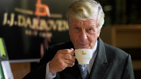 Kaffee-Unternehmer Albert Darboven im Jahr 2015 mit einer Tasse Kaffee vor einem Firmenschild. © picture alliance / Sven Simon Foto: Frank Hoermann / Sven Simon