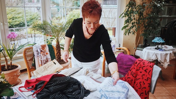 Frau Schuldt legt ihre bunten DDR-Kleider auf den Tisch. © Hannes Wichmann Foto: Hannes Wichmann
