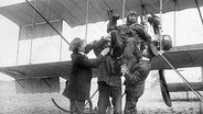 Pilot Benno König, Gewinner des ersten Deutschlandflugs 1911, wird von seinen Freunden beim Aussteigen aus dem Flugzeug gefeiert | Creative Commons CC0 License © gemeinfrei/ Creative Commons CC0 License 