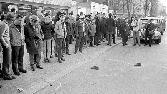 Am Berliner Kurfürstendamm, wo der Studentenführer Rudi Dutschke kurz zuvor niedergeschossen wurde, schauen Passanten am 11. April 1968 auf dessen von der Polizei markierten Schuhe. © picture-alliance / dpa Foto: Chris Hoffmann