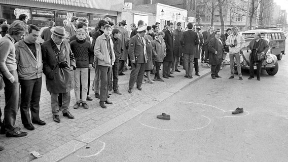 Am Berliner Kurfürstendamm, wo der Studentenführer Rudi Dutschke kurz zuvor niedergeschossen wurde, schauen Passanten am 11. April 1968 auf dessen von der Polizei markierten Schuhe. © picture-alliance / dpa Foto: Chris Hoffmann