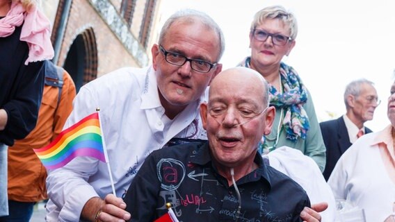 Reinhard Lüschow (l.) und Heinz-Friedrich Harre posieren am 01.10.2017 nach ihrer Eheschließung im Alten Rathaus in Hannover mit einem Regenbogen-Fähnchen für ein Foto. © picture alliance Foto: Philipp von Ditfurth