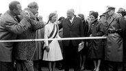 Ein Mädchen durchschneidet am 30. April 1963 zur Einweihung der neuen Fehmarnsundbrücke ein weißes Band. © picture-alliance / dpa Fotoreport 