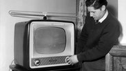 Ein Mann bedient in den 50er-Jahren ein Fernsehgerät. © picture alliance / akg-images | akg-images / Paul Almasy 