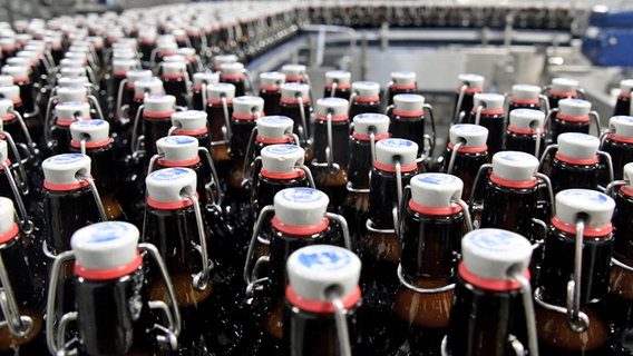 Bierflaschen laufen über ein Band in der Flensburger Brauerei. © dpa Foto: Carsten Rehder