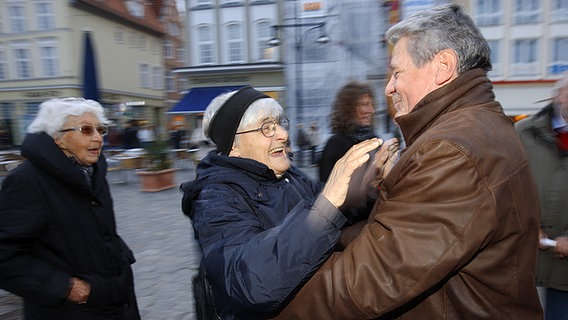 Der frühere Bundesbeauftragte für die Stasi-Unterlagen, Joachim Gauck (r), wird im Oktober 2009 in Rostock vor einer Demonstration  mit Bürgerrechtlern und Gemeindemitgliedern von einer Frau begrüßt. © picture-alliance/ dpa Foto: Jens Büttner