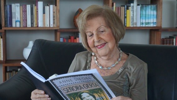 Eine Frau schaut in ein Buch und lächelt dabei. © Anne Siegel 