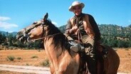Der US-amerikanische Schauspieler Lorne Greene reitet in einer Szene der beliebten Western-Serie "Bonanza" als Familienoberhaupt "Ben Cartwright" auf einem Pferd. © picture-alliance / dpa Foto: Bert Reisfeld