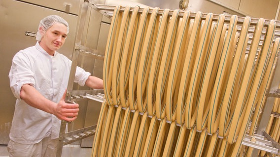 Ein Auszubildender der Firma Greifenfleisch GmbH Greifswald bereitet eine neue Charge Currywurst zum Räuchern vor. Ein Auszubildender der Firma Greifenfleisch GmbH Greifswald bereitet eine neue Charge Currywurst zum Räuchern vor. © dpa Foto: Stefan Sauer