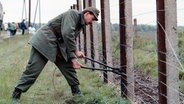 Ein Grenzsoldat durchschneidet den Zaun zwischen Österreich und Ungarn, 2. Mai 1989. © dpa 