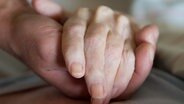 Ein Altenpfleger hält in einem Pflegeheim die Hand einer Frau. © picture alliance/dpa/dpa-Zentralbild Foto: Sebastian Kahnert