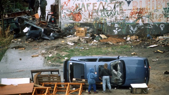 Umgestürzte Fahrzeuge und Holzgestelle als Barrikade vor einem mit Graffiti bemalten Haus in der Hamburger Hafenstraße am 12. November 1987. © picture-alliance / dpa Foto: Carsten Rehder