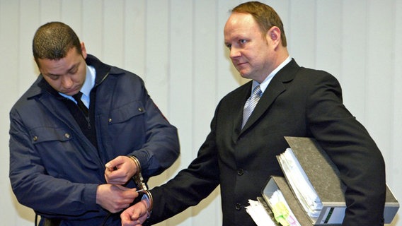 Ein Justizangestellter befreit den Angeklagten Jürgen Harksen (r) am 28. März 2003 vor Beginn des Prozesses vor der Wirtschaftsstrafkammer des Hamburger Landgerichts von Handschellen © picture-alliance / dpa | DB Fabian Bimmer 